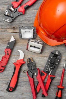 Gri ahşap bir masadaki elektrikçi ya da inşaatçının aletleri. İnşaat aletleri: masada kramplar, bıçak, eldivenler ve mezura var. Metin için boşluk olan üst görünüm
