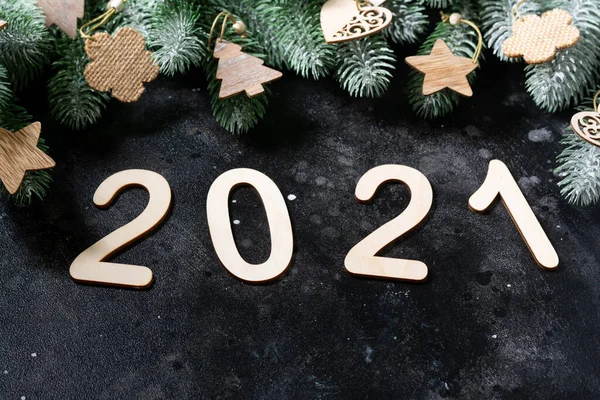 Happy New year 2021. Wooden Christmas or new year decorations on Christmas tree branches. Christmas background with wooden numbers 2021