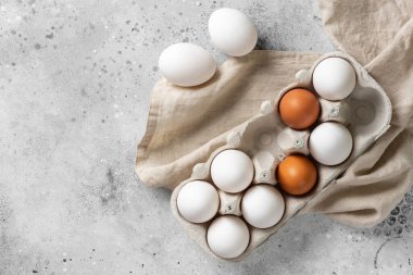 Mutfak masasındaki tepside yumurtalar. Pişirmek için beyaz ve kahverengi yumurtalar. Mutfak arka planında bir tepside tavuk yumurtası. Pişirme hazırlığı kavramı. Metin için boşluk olan üst görünüm