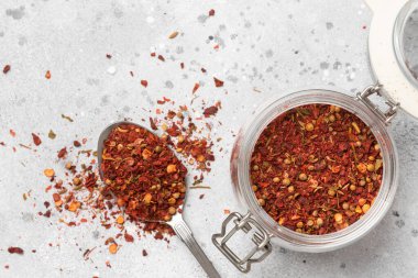 Baharat karışımı: kırmızı biber, baharat, kişniş, kurutulmuş domates. Açık gri mutfak masasındaki cam kavanozdaki farklı baharatların karışımı. Metin için boşluk olan üst görünüm