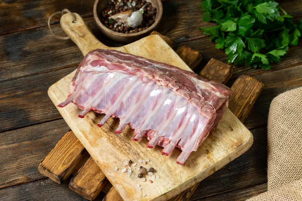 Lamb meat. Lamb ribs on a wooden chopping Board on a brown wooden table. Raw lamb meat on the table, loin