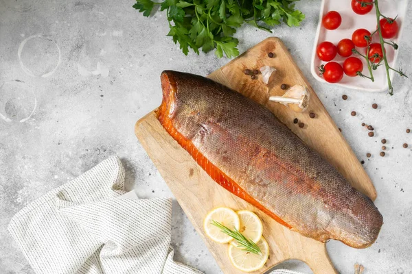 Tütsülenmiş balık. Servis kurulunda tütsülenmiş alabalık. Açık gri mutfak masasında tütsülenmiş alabalık yatıyordu. Yakından tütsülenmiş balık. Metin için boşluk olan üst görünüm
