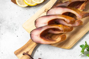 Tütsülenmiş balık. Servis kurulunda füme balık bifteği. Açık gri mutfak masasında dilimlenmiş omul balığı. Balıklar yakın.