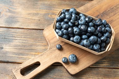 Kahverengi ahşap bir masada, ahşap bir kutuda yabanmersini. Kutuda taze yaban mersini. Metin için boşluk olan üst görünüm