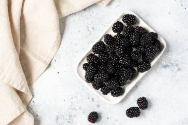 Böğürtlen Arka planda beyaz bir tabakta böğürtlen. Kasede taze böğürtlen. Metin için boşluk olan üst görünüm