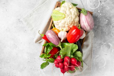 Tahta bir kutuda sebze çeşitleri. Sepette bir sürü farklı çiğ sebze var. Turp, sarımsak, karnabahar, masada tatlı biber ve patlıcan. Sağlıklı gıda konsepti. Üst görünüm