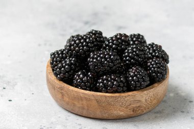 Çilek. Böğürtlenler, lamba sehpasında, tahta bir kasede. Yakın plan çekimde taze böğürtlen. Metin için boşluk
