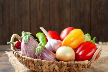 Masadaki sepetin içinde sebze çeşitleri. Sepette bir sürü çiğ sebze var. Patlıcan, domates, sarımsak, tatlı biber, masada soğan. Sağlıklı beslenme kavramı