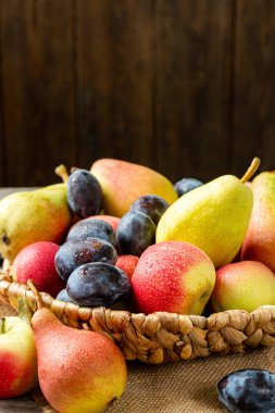 Masadaki sepetin içinde meyve çeşitleri. Sepette bir sürü farklı çiğ meyve var. Erikler, şeftaliler, elmalar ve armutlar masada. Sağlıklı gıda konsepti