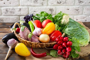 Masadaki sepetin içinde sebze çeşitleri. Sepette bir sürü çiğ sebze var. Patlıcan, domates, sarımsak, tatlı biber, masada soğan. Sağlıklı gıda konsepti