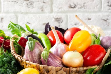Masadaki sepetin içinde sebze çeşitleri. Sepette bir sürü çiğ sebze var. Patlıcan, domates, sarımsak, tatlı biber, masada soğan. Sağlıklı gıda konsepti