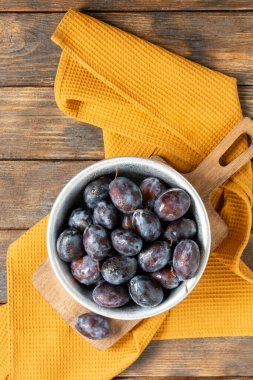 Olgun erik. Kahverengi ahşap bir masada metal bir kasede bir sürü erik. Kasedeki mavi erikler. Metin için alanı olan üst görünüm. Sağlıklı meyve