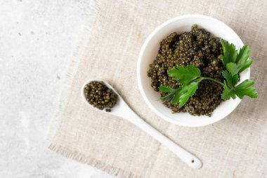 Siyah havyar. Seramik kasede siyah mersin balığı havyarı ve arka planda seramik kaşıkta. Faydalı bir lezzet. Metin için boşluk olan üst görünüm