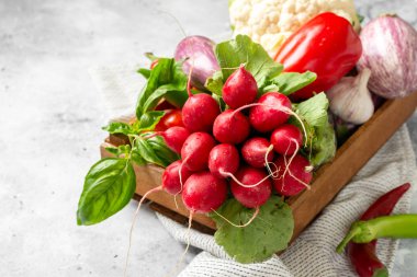 Sebze çeşitleri masanın üzerindeki tahta kutuda. Sepette bir sürü çiğ sebze var. Masada turp, sarımsak, tatlı biber ve patlıcan var. Sağlıklı beslenme kavramı. Yakın çekim.
