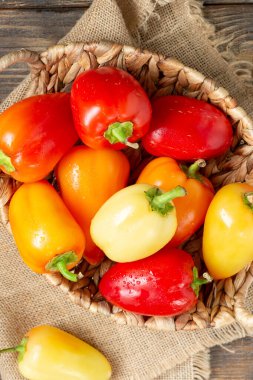 Tatlı biber. Kahverengi ahşap bir masada kırmızı, sarı ve turuncu biberler. Paprika yakın plan