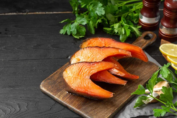 Tütsülenmiş balık. Servis kurulunda füme balık bifteği. Dilimlenmiş alabalık ahşap mutfak masasında yatıyordu. Tütsülenmiş alabalık.