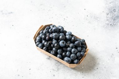 Hafif arka planda ahşap bir kutuda yabanmersini. Kutuda taze yaban mersini. Metin için boşluk olan üst görünüm