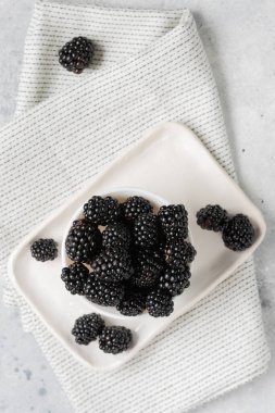 Böğürtlen Arka planda beyaz bir tabakta böğürtlen. Kasede taze böğürtlen