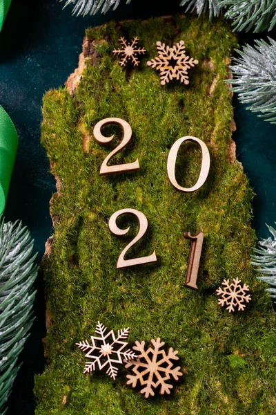 Happy new year 2021. Wooden Christmas or new year decorations on the branches of the tree. Christmas background with wooden numbers 2021. Eco decorations