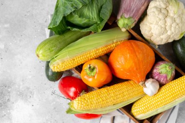 Sebzeler. Tahta bir kutuda taze çiğ mısır, balkabağı, tatlı biber, lahana ve sarımsak. Sonbahar hasadı konsepti. Sebzeler kapanıyor.