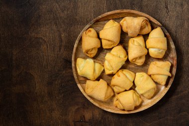 Bir sürü simit. Kahverengi bir masada, ahşap bir tabakta puf böreği. Kurabiyeler yakın plan. Metin için boşluk olan üst görünüm