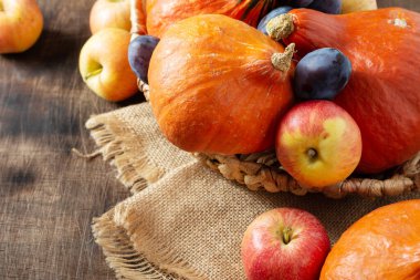 Hokkaido balkabakları, elmalar ve erikler gri ahşap bir masanın üzerine serilmiştir. Sonbahar hasadı konsepti. Şükran Günü