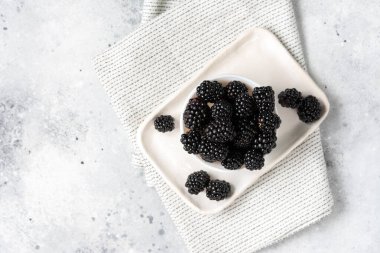 Böğürtlen Arka planda beyaz bir tabakta böğürtlen. Kasede taze böğürtlen