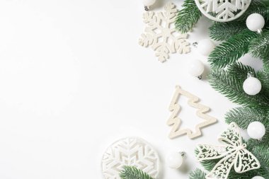 Noel arkaplanı. Beyaz arka planda ladin dalları üzerine beyaz süslemeler. Düz Noel. Kopyalama uzayından en üst görünüm