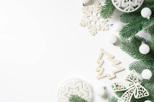 Noel arkaplanı. Beyaz arka planda ladin dalları üzerine beyaz süslemeler. Düz Noel. Kopyalama uzayından en üst görünüm