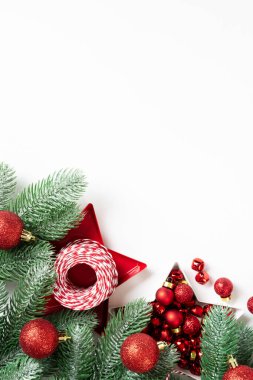 Noel arkaplanı. Beyaz arka planda ladin dallarına kırmızı süslemeler. Düz Noel. Kopyalama uzayından en üst görünüm