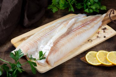 Morina filetosu. Kahverengi mutfak masasında çiğ balık filetosu. Balık pişirme hazırlığı