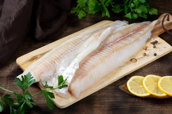 Morina filetosu. Kahverengi mutfak masasında çiğ balık filetosu. Balık pişirme hazırlığı
