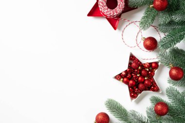 Noel arkaplanı. Beyaz arka planda ladin dallarına kırmızı süslemeler. Düz Noel. Kopyalama uzayından en üst görünüm