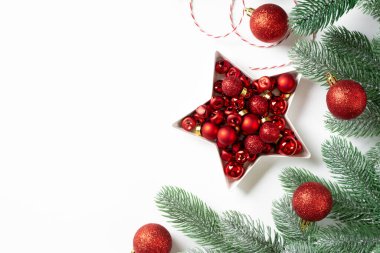 Noel arkaplanı. Beyaz arka planda ladin dallarına kırmızı süslemeler. Düz Noel. Kopyalama uzayından en üst görünüm