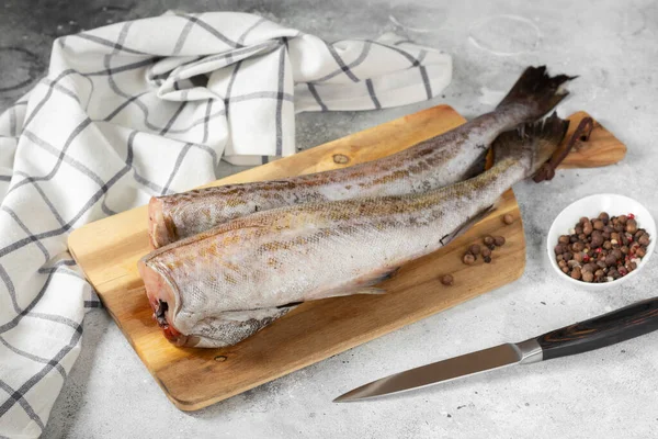 Pollock fish. Raw pollock on a chopping Board on a light gray kitchen table. Preparation for cooking fish