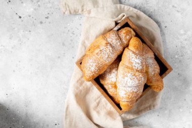 Ay çöreği. Açık gri arka planda tahta bir kutuda kruvasanlar. Fransız pastası. Metin için boşluk olan üst görünüm