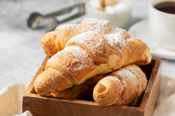 クロワッサンだ 薄い灰色の背景に木製の箱のクロワッサン フランスの朝食 クロワッサンが接近 — ストック写真