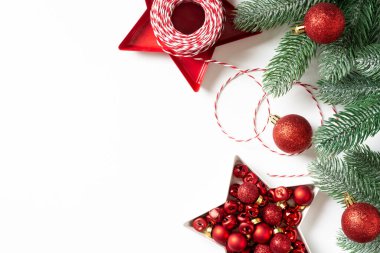 Noel arkaplanı. Beyaz arka planda ladin dallarına kırmızı süslemeler. Düz Noel. Kopyalama uzayından en üst görünüm