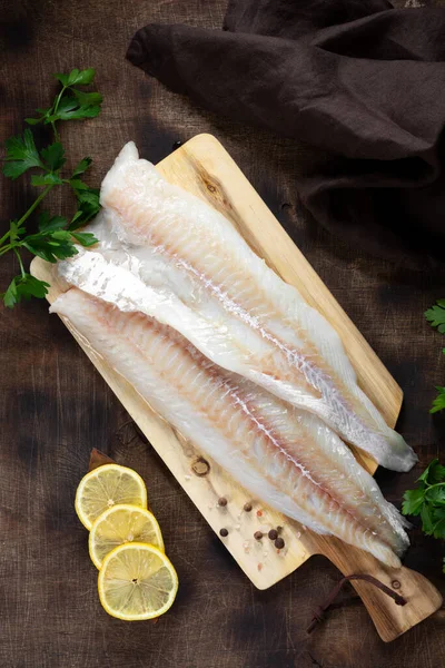 Morina filetosu. Kahverengi mutfak masasında çiğ balık filetosu. Balık pişirme hazırlığı. Üst görünüm