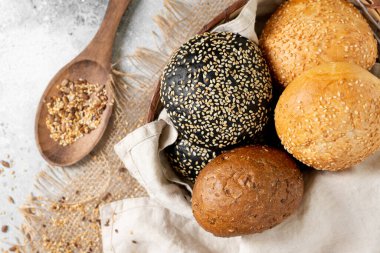 Hamburger için susamlı çörek. Açık gri arka planda bir sepette buğday ve çavdar ekmeği. Susamlı ev yapımı çörekler. Üst Manzara. Kopyalama alanı