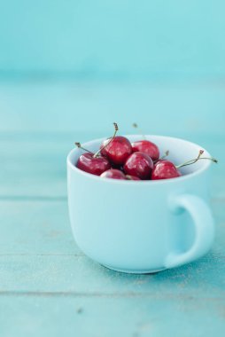 Mavi bir fonda mavi bir fincanda olgun kirazlar.