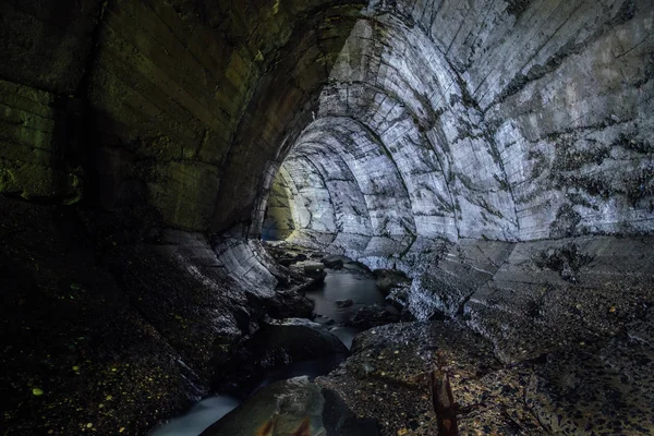 Underground river flowing through large oviform underground turning drainage sewer tunnel — Stock Photo, Image