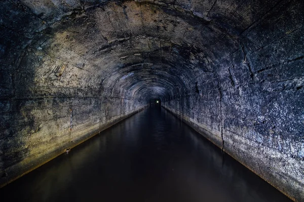 Túnel de la mina de drenaje abovedado de hormigón inundado oscuro — Foto de Stock