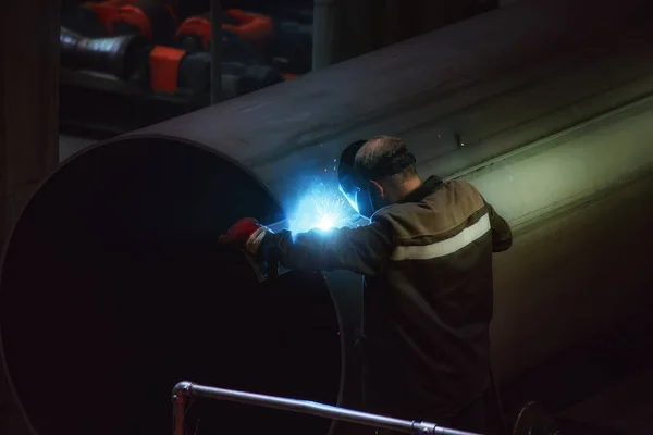 Работник защитной маски сварки труб на заводе — стоковое фото