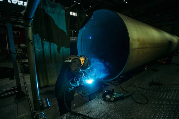Работник защитной маски сварки труб на заводе — стоковое фото