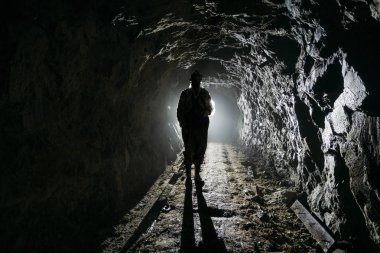 Karanlık terk edilmiş maden içinde ürpertici arkadan aydınlatmalı insan silueti
