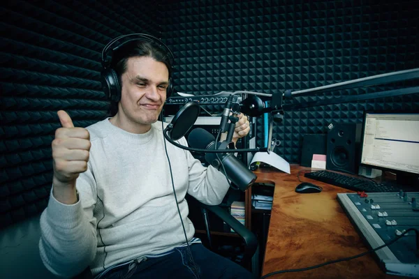 Smiling talking radio DJ shows thumbs up in radio studio
