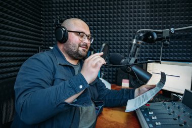 Gülümseyen erkek radyo sunucusu radyo istasyonunda kağıt üzerinde metin okuyun