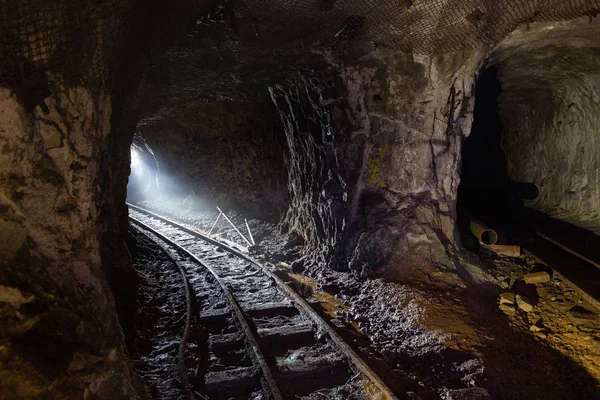 Tmavý špinavý, opuštěný uranový důl s rezavými zbytky železnice — Stock fotografie