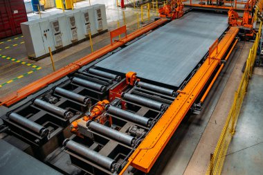 Metal işleme atölyesinde silindir konveyör üzerinde hareket eden çelik sac